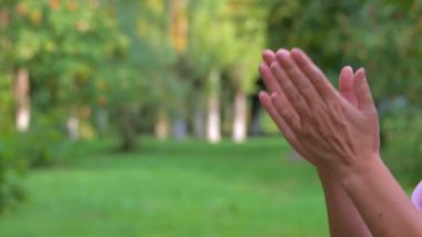 Kadınların elleri avuçlarını yeşil doğanın arka planına doğru çırpıyor.