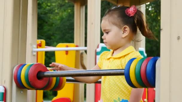 Smiling little girl is playing in the park. She has fun on carousel — Stock Video