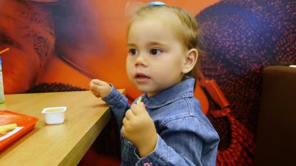 Niña comiendo papas fritas en la cafetería — Vídeo de stock