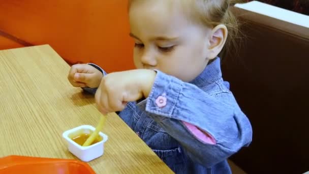 Μικρό κορίτσι τρώει πατάτες τηγανιτές σε καφετέρια — Αρχείο Βίντεο