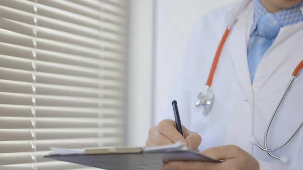 Médico varón haciendo papeleo en el consultorio. — Foto de Stock