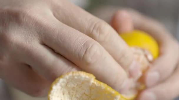 A man cleans tangerine on the table. Hands are peeling fresh tangerine. — Stock Video