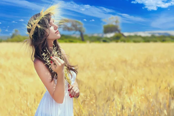 Morena em um vestido branco de pé em um campo de trigo. — Fotografia de Stock