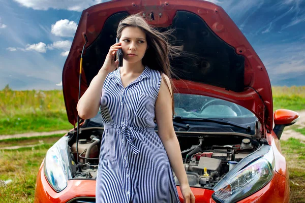 Donna con una macchina rotta sulla strada rurale sta chiamando sul telefono cellulare. — Foto Stock