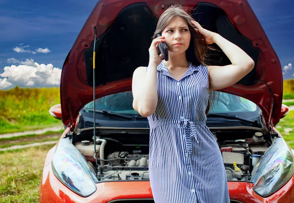 Donna con una macchina rotta sulla strada rurale sta chiamando sul telefono cellulare. — Foto Stock