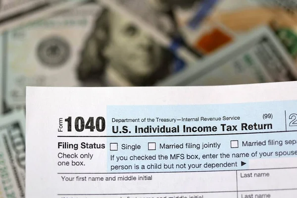 One hundred dollar bills and US 1040 tax form.