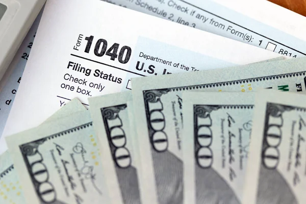 US individuale 1040 forma fiscale, calcolatrice e banconote da cento dollari — Foto Stock