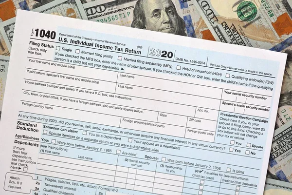 One hundred dollar bills and US 1040 tax form.