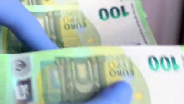 Hände mit blauen Schutzhandschuhen zählen 100-Euro-Banknoten — Stockvideo