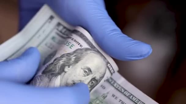 Las manos con guantes médicos azules están contando billetes de 100 dólares — Vídeo de stock