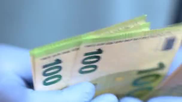 Hands with blue protective medical gloves are counting 100 EURO money banknotes — Stock Video