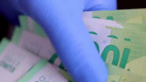 Las manos con guantes médicos protectores azules están contando billetes de 100 euros — Vídeo de stock