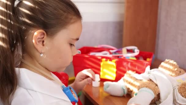 Dziecko dziewczyna noszenie w biały medyczny mundur zabawy z miś — Wideo stockowe