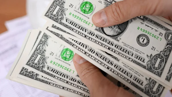 Een man die amerikaanse dollarbiljetten van dichtbij telt — Stockfoto