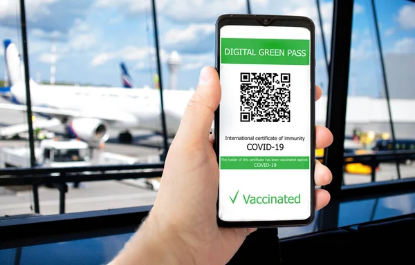 The digital green pass with the QR code on the screen of a mobile in a man hand