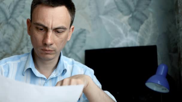Um homem frustrado sentado à secretária com notas de papel. Conceito de falência — Vídeo de Stock