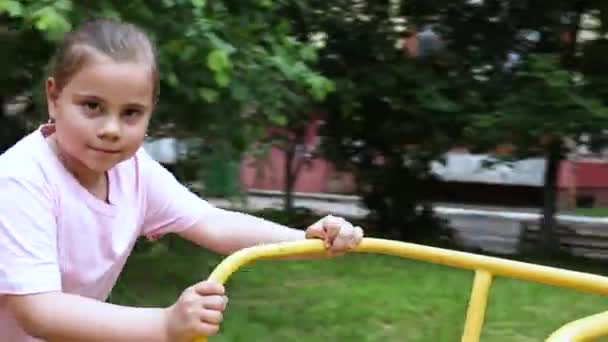 A little child girl playing on playground. Girl running with a carousel. — Stock Video