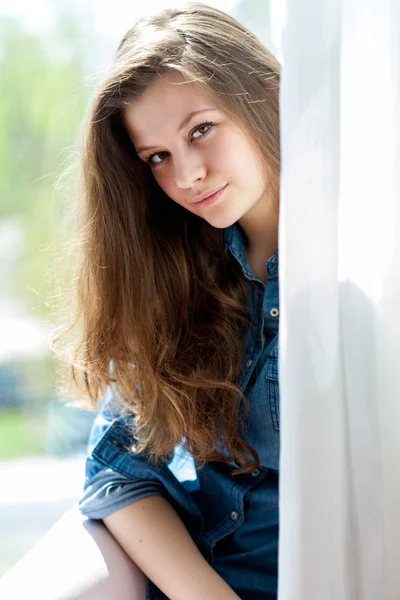 La mujer está mirando por la ventana. — Foto de Stock