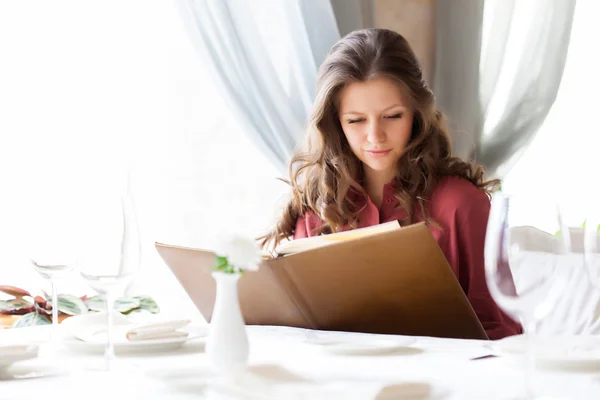 Eine Frau in einem Restaurant mit dem Menü in der Hand — Stockfoto