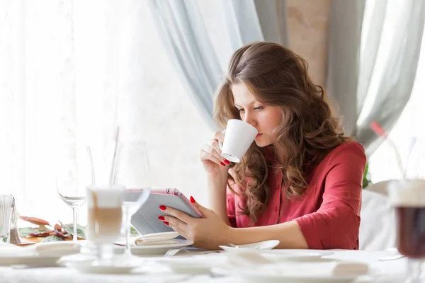 Young smiling woman is drinking coffee in a cafe — Stock Photo, Image