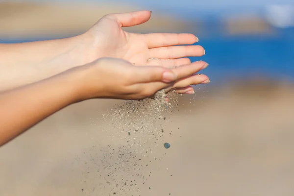 Een vrouw met zand door middel van haar handen van vallen — Stockfoto