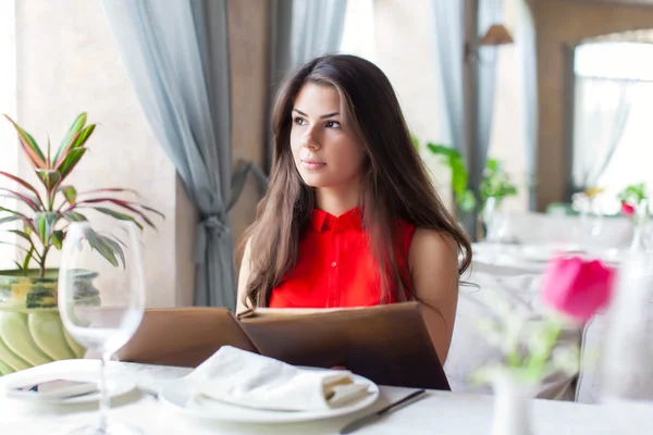 Een vrouw in een restaurant met het menu in handen — Stockfoto