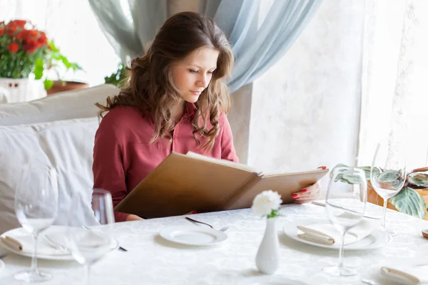 En kvinna i en restaurang med menyn i händer — Stockfoto
