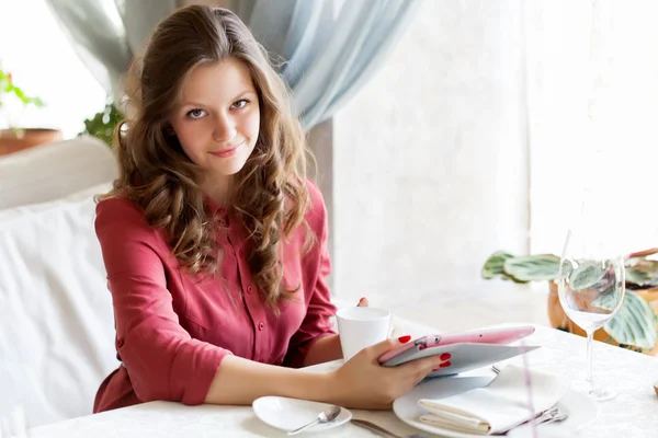 Jonge lachende vrouw drinkt koffie in een café — Stockfoto