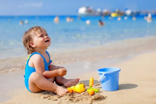 Little girl in blue swimsuit is playing in water — Stock Photo, Image