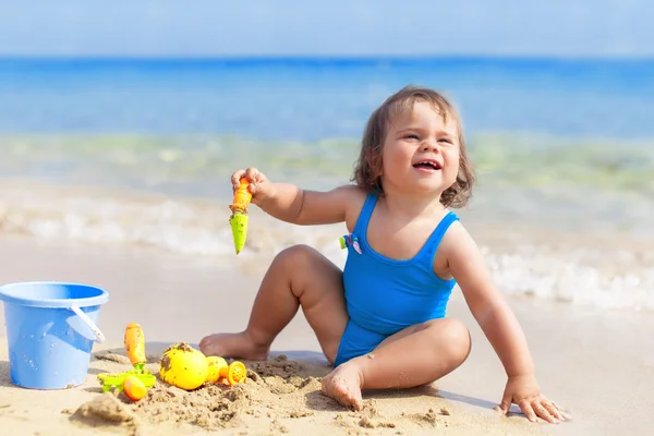 Little girl in blue swimsuit is playing in water — Stock Photo, Image