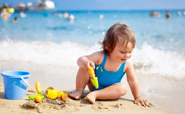 Petite fille en maillot de bain bleu joue dans l'eau — Photo