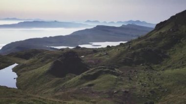Yüksek keskin uçurumların atmosferik üst görüntüsü şafaktan önce alçak bulutlarla kaplı göller ve deniz üzerinde yükseliyor.