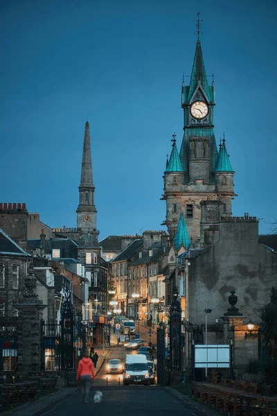 Akşamları eski tarihi bir şehrin caddesinde yürüyen insanlar ve sokak lambaları.