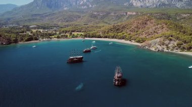 Arka planda Olimpos Dağı ve yelkenli gemileriyle Phaselis Körfezi 'nin havadan görünüşü. Türkiye 'nin Antalya kenti yakınlarındaki berrak mavi su ve manzaralı Akdeniz kıyıları. Türkiye 'de manzaralı kıyı güzelliğini yakalıyor.