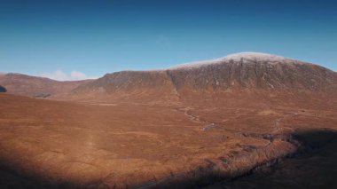 Sarmal bir nehir ve sabah İskoçya 'daki dramatik dağ manzarasının insansız hava aracı videosu. Uzak vahşi doğa manzaralı İskoçya 'da alacakaranlıkta