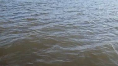 Dalgalanan küçük, rüzgârlı dalgalarla karanlık su yüzeyinin görüntüsünü kapat