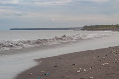Plastik atıkla kirletilmiş siyah kum plajı