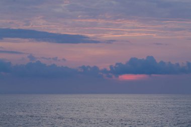 Derin deniz ufkunun üzerinde huzurlu mor gün batımı.