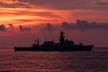 Askeri gemi yoğun günbatımında yelken açıyor.