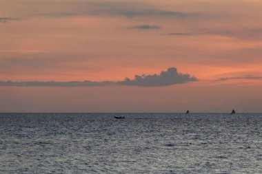 Gün batımında Uzak Balıkçı tekneleri, Sahne Sahnesi için Dramatik Gökyüzü ve Su Yansımaları ile Huzurlu Okyanus Görünümü