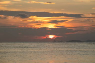 Okyanus manzaralı günbatımı dramatik bulutlar ve sıcak doğal ışık ile yansıyor. Sakinleştirici deniz manzarası yaratıyor. Yolculuk için mükemmel.