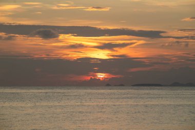 Okyanus suyunun üzerinde güzel altın gün batımı geniş açılı dramatik bulutlarla doğa için sakin deniz manzarasını yakalıyor.