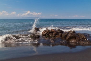Dalgalar, su püskürtücü ve mavi gökyüzü ile karanlık kıyı kayalarına çarpıyor. Doğa aşıkları için mükemmel ve HDR 'de seyahat ilhamı yaratıyor.