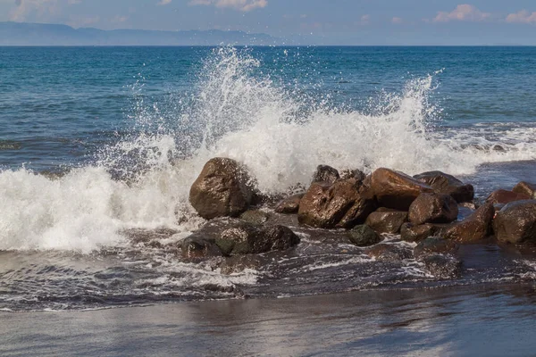 Dinamik okyanus dalgası doğal ışık altında kayalara çarpıyor. Kopyalama alanı ile birlikte. Sahil gücünü ve çevresel değişimi göstermek için ideal.