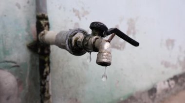 Doğal ışık altındaki eski bir musluktan damlayan su, su krizini ve mevcut fotokopi alanı ile suyu korumanın aciliyetini simgeliyor.