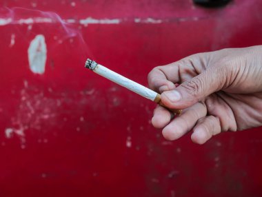 Kırmızı arka planda el ele sigara içmek, bağımlılık ve sağlık risklerini vurgulamak sigara karşıtı kampanyalar için doğal ışık altında