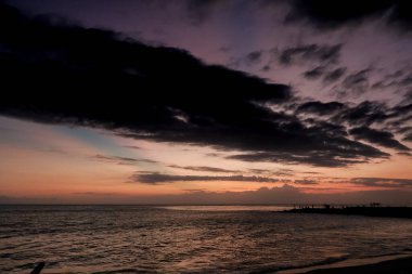Karanlık bulutlarla okyanusun üzerinde gün batımı çarpıcı bir kontrastlık yaratır, doğal ışık deniz manzarasının güzelliğini ve sükunetini yakalar, yolculuk için mükemmeldir.