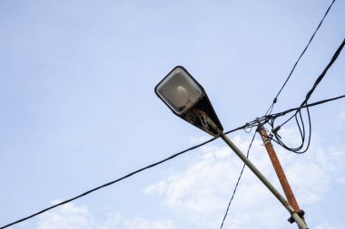 Elektrik hatları yumuşak mavi gökyüzüne karşı geçen eski sokak lambası altyapı ve şehir planlama projeleri için fotokopi alanı sunuyor