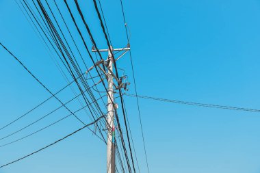 Wooden transmission pole and multiple power cables over vibrant blue sky, creating ample copy space, symbolizing energy and infrastructure themes