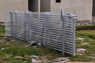 İnşaat sahasında yığılmış metal çitler, doğal ışık altında endüstriyel ve güvenlikle ilgili temalara uygun geniş bir kopyalama alanı ve sergilenecek inşaat malzemesi sağlıyor